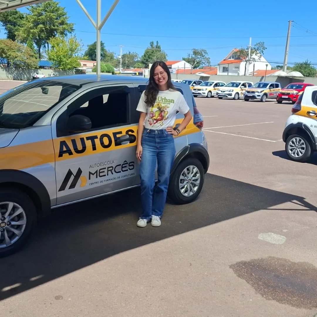 Aluna ao lado do carro da Autoescola Mercês